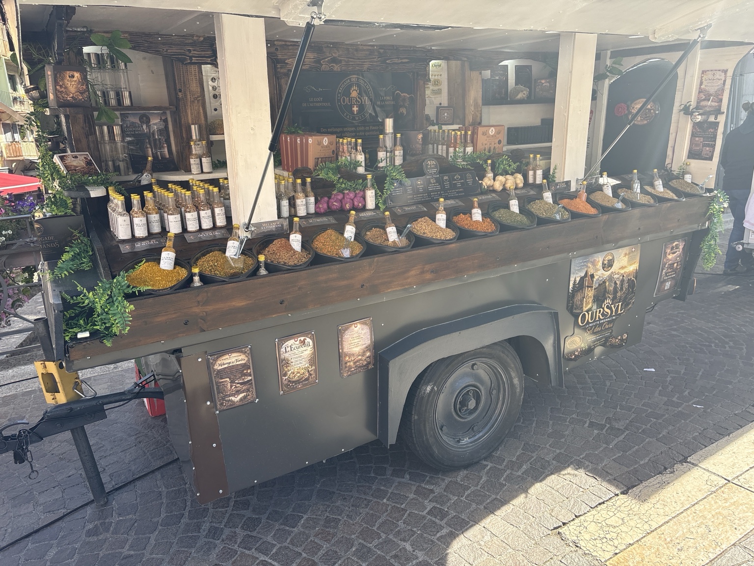 Vue rapprochée du stand : bacs de mélanges en vrac, fioles dorées, coffrets et produits OURSYL
